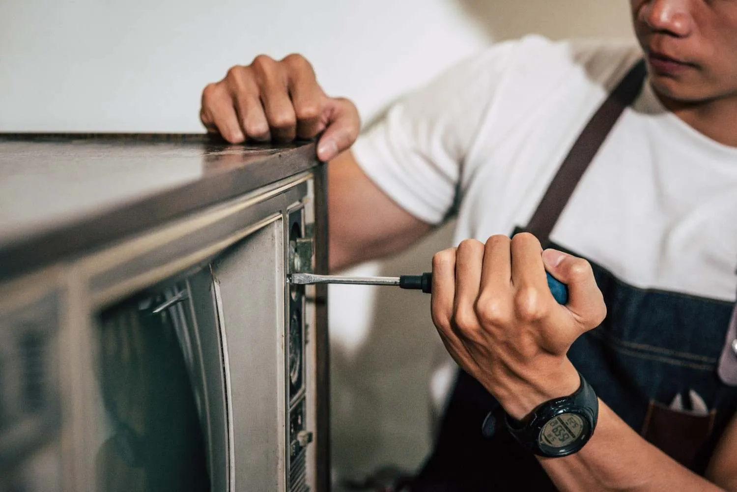 Technician using a screwdriver on a kitchen appliance